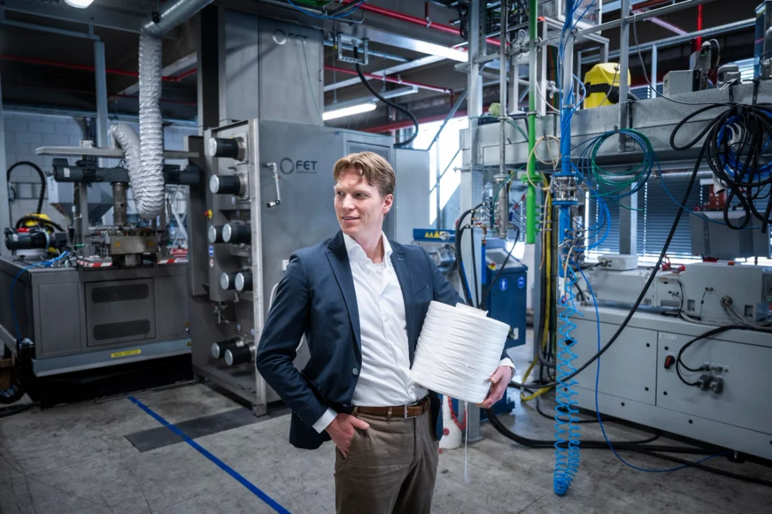 Senbis managing director Gerard Nijhoving standing in an industrial space holding a spool of biopolyester.