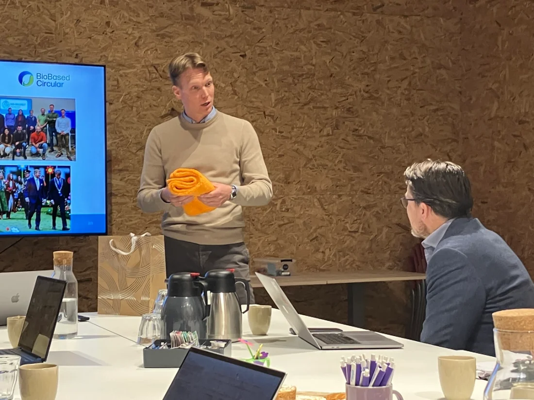 Gerard Nijhoving talks to Prince Constantin of the Netherlands holding orange BioFur prototype scarves.